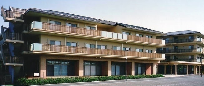 3階建ての介護施設の建物外観。モダンなデザインで複数のバルコニーを備えている。